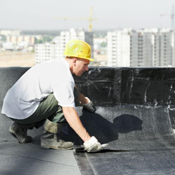Roofing Guys Melbourne technician installing a waterproofing membrane on a commercial rooftop as part of regular strata and building maintenance services. Roofing Guys Melbourne technician installing a waterproofing membrane on a commercial rooftop as part of regular strata and building maintenance services.