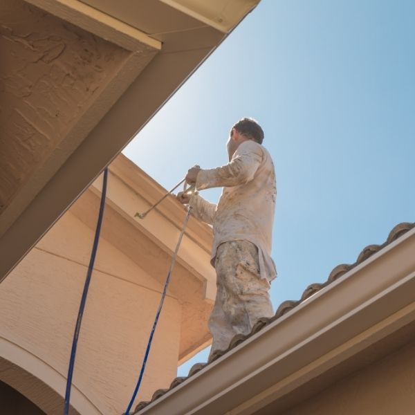 Painter applying roof painting coatings to a residential roof in Melbourne to restore colour and extend its lifespan.