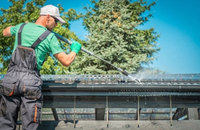 Professional gutter cleaning in Melbourne by Roofing Guys team using pressure washing to remove built-up dirt and leaves.