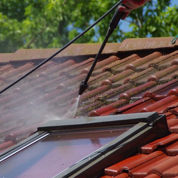 Roofing Guys Melbourne performing roof cleaning with a pressure washer to clear mould and dirt from red roof tiles.