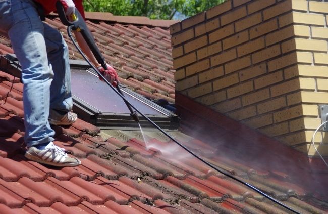 Roofing Guys Melbourne team performing professional roof cleaning with a pressure washer to restore tile colour and shine.